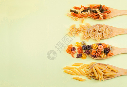 各种意大利面食 Farfalle 黄色背景上木勺上的 fusilli 顶视图 复制空间图片