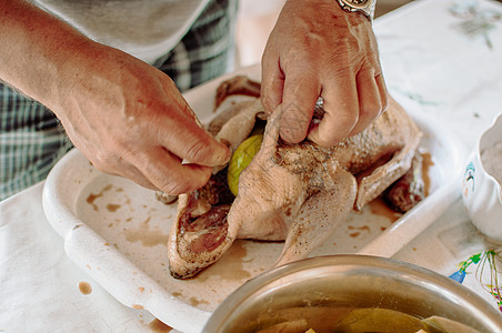 整只鸭新鲜生在托盘上 配料准备烹饪和烘烤香料 一个男人开始做苹果馅的北京烤鸭 烹饪食谱的概念图片