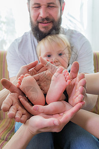 父母和子女将婴儿的脚跟握在手掌中母性一家人儿子生活身份健康拥抱家庭手指喜悦图片