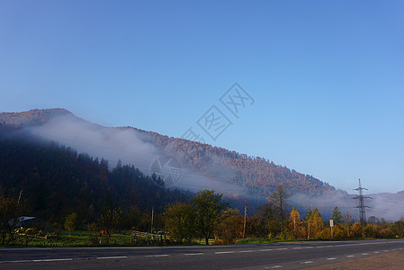 山上美丽的风景 森林中雾雾 福吉和山地 汽车在乡村公路上行驶 路边村庄图片