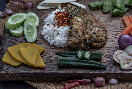 当地泰国食品风格的煎蛋或茉莉米上的热蛋 其配料和新鲜蔬菜在木制背景上猪肉噼啪辣椒午餐烹饪羽状早餐油炸草本植物食物图片
