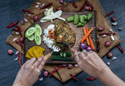 泰国当地的美食风格 手用勺子在茉莉花米饭上舀油炸金合欢煎蛋卷或 chaom 鸡蛋 配料和木制背景上的新鲜蔬菜食物猪肉黄瓜午餐烹饪图片