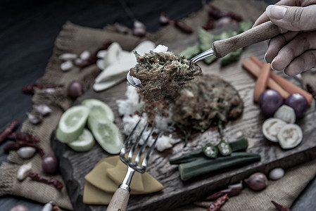 泰国当地的美食风格 手用勺子在茉莉花米饭上舀油炸金合欢煎蛋卷或 chaom 鸡蛋 配料和木制背景上的新鲜蔬菜早餐噼啪辣椒营养茄子图片