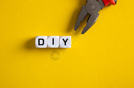 在黄色背景上带有 DIY 字词的区块 DIY 概念家居改造建筑项目修理工螺丝刀工具工作装修服务背景图片