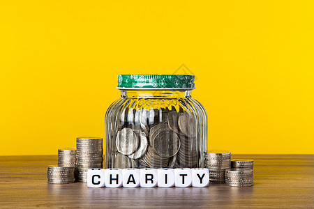 玻璃罐中有很多有黄色背景的硬币 拯救慈善概念捐赠服务财富桌子玻璃现金金融团队机构商业图片