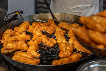 钢锅上热油的中国深炸面团或炸面粉棒午餐小吃平底锅面包食物甜点早餐油条盘子烹饪图片