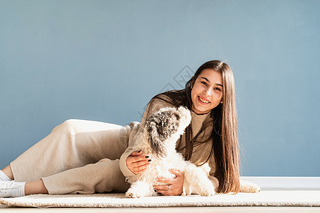 漂亮的女人 带着玩乐的狗 在家里拥抱快乐闲暇蓝色女士友谊小狗幸福女性犬类朋友图片