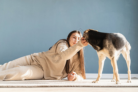 漂亮的女人 带着玩乐的狗 在家里拥抱快乐犬类蓝色幸福训练喜悦乐趣微笑成人友谊图片