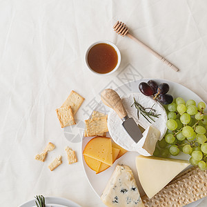 配有蜂蜜 葡萄 面包和迷迭香的奶酪板板类美食木板蓝色桌子甜点山羊盘子产品羊乳水果图片