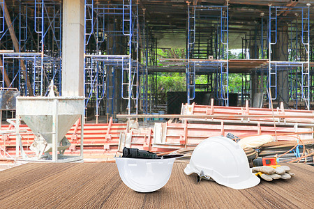两个白色安全帽和皮手套卷尺 卷纸计划蓝图 用于工程工作内部建筑工地建筑在木地板桌上 复制空间添加文本 模糊背景商务工程师石膏安装图片