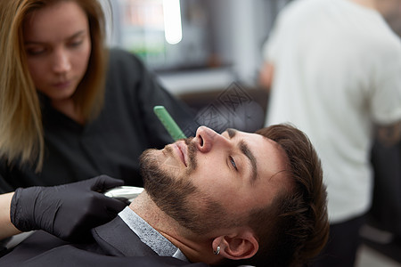 在现代理发店剪胡子的英俊男郎 女理发师切胡子服务头发男人胡须顾客刀刃椅子职业发型师治疗图片