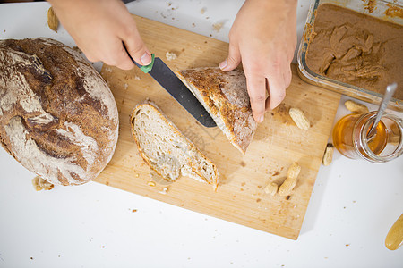 女性用手在切割板上切面包砧板坚果烹饪玻璃美食桌子午餐早餐小吃勺子图片