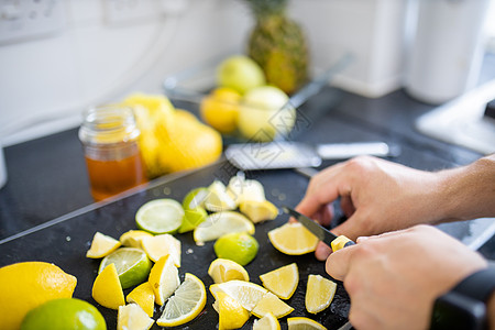 男性手在黑盘上切柠檬和石灰容器水果茶点托盘团体热带果汁烹饪蜂蜜玻璃图片