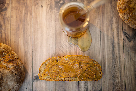 蜂蜜罐子和一小片面包 木制桌上有花生酱甜点盘子早餐花生糖浆营养小吃饮食小麦食物图片