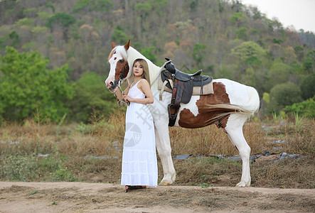 穿着裙子的女性在日落时 在田地风景中骑马对抗天空骑术骑士闲暇骑师动物运动友谊荒野马术牛仔图片