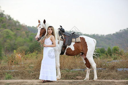 穿着裙子的女性在日落时 在田地风景中骑马对抗天空动物运动宠物女士场地友谊闲暇骑术荒野农场图片