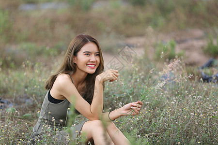 一个美丽的女人 长发穿着裙子 坐在草地上 在夜光中花朵和鲜花马术闲暇农场爱好马背幸福女士骑术友谊农村图片