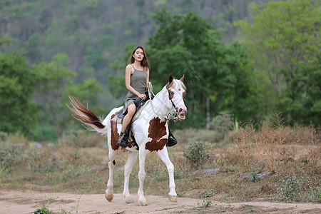 穿着裙子的女性在日落时 在田地风景中骑马对抗天空场地马术骑师女孩运动骑士动物牛仔闲暇荒野图片