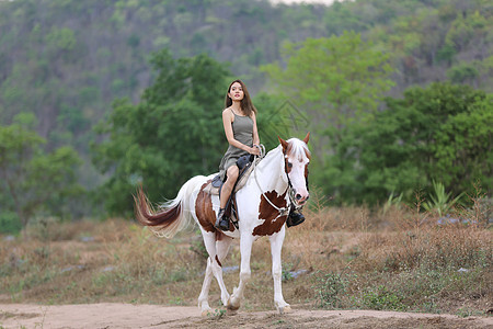 穿着裙子的女性在日落时 在田地风景中骑马对抗天空友谊马背场地农场骑士牛仔女士女孩农村运动图片