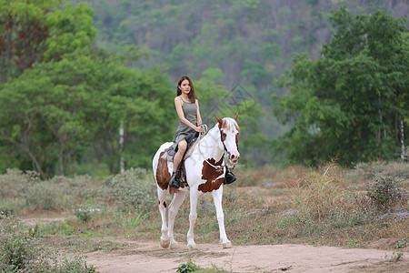穿着裙子的女性在日落时 在田地风景中骑马对抗天空闲暇骑术骑师马术爱好女孩骑士女士运动牧场图片