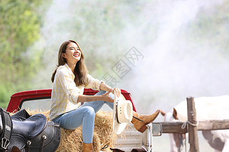 一名身着女牛仔风格的妇女坐在西部农场环境的马场里女孩场地宠物闲暇友谊哺乳动物马术女性骑术运动图片