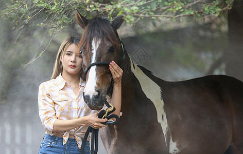 一名身着女牛仔风格的妇女坐在西部农场环境的马场里农村运动哺乳动物农场女士闲暇动物骑士女性马术图片