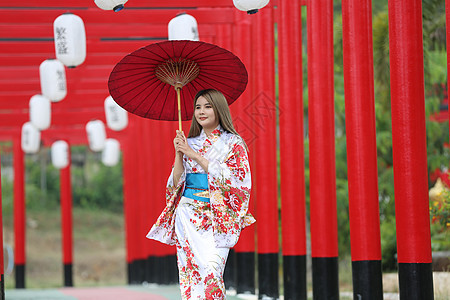 穿着和服的女人拿着伞走进来 在圣殿红门 在日本花园神道女性女孩艺妓戏服旅行传统神社宗教文化图片