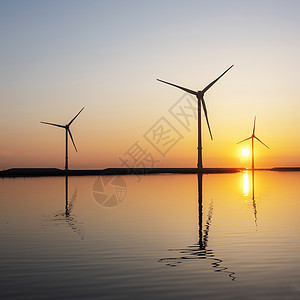 水中反射的风力涡轮机和彩色日出天空技术公园环境太阳发电机海洋风车生态活力图片