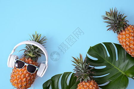 穿着白色耳机的有趣的菠萝 在蓝色背景中被孤立食物太阳镜假期平铺凤梨眼镜乐趣热带高架水果图片