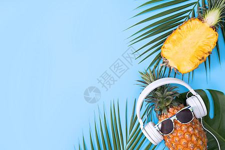穿着白色耳机的有趣的菠萝 在蓝色背景中被孤立乐趣眼镜棕榈高架食物叶子热带海滩太阳镜潮人图片