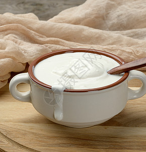 棕色陶瓷碗中的酸奶油和木板上的木勺子桌子酸奶食物产品营养盘子牛奶奶制品白色鞭打图片