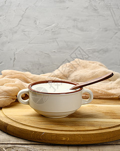 棕色陶瓷碗中的酸奶油和桌上的木勺子牛奶桌子产品鞭打白色奶制品盘子酸奶营养食物图片