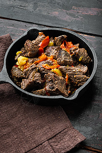 牛肉炖萝卜Bangin 牛肉炖肉 在烤铁煎锅中 用旧的黑木制餐桌背景