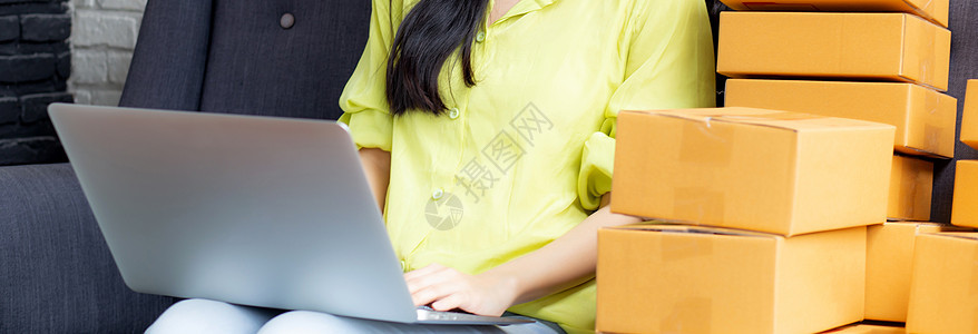 年轻的亚洲女性是商务人士 在沙发上使用笔记本电脑检查客户的订单 购买网上购物 商业中小企业或初创企业 企业家或卖家以及服务交付产图片