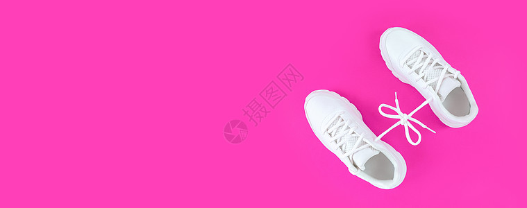 运动鞋海报一双白色运动鞋 与粉红色背景的蕾丝弓相连接 简单平坦 有复制空间背景