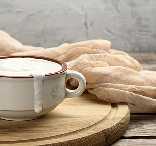 棕色陶瓷碗中的酸奶油和木板上的木勺子餐巾奶制品桌子鞭打食物产品酸奶营养白色盘子图片