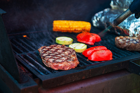 烤炉上牛肉牛排和火焰烧烤架蔬菜派对牛肉肋骨香肠网格炙烤野餐烧伤图片