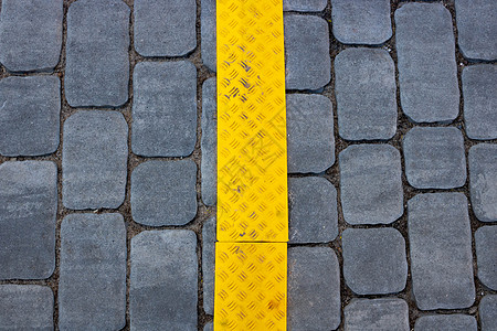 街道上带有黄色条纹的灰色铺路板的质地很有前景 水泥砖方形石地板背景 人行道路面啪嗒啪嗒图片