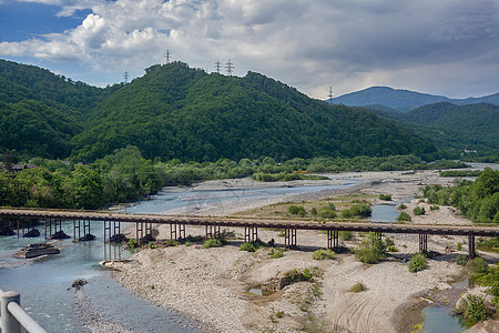 山河上的旧桥岩石绿色多云石头山脉流动溪流森林图片