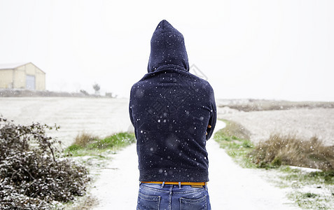 下雪的年轻人橙子雪花蓝色外套男性街道城市暴风雪风暴天气图片