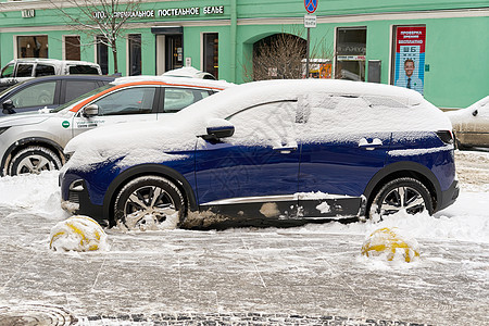 一辆被雪覆盖的汽车停在圣彼得堡市街道上图片