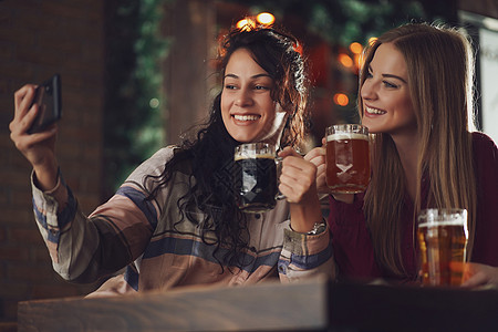 酒吧里的朋友成人啤酒厂手机快乐女性咖啡店微笑讨论啤酒杯啤酒图片