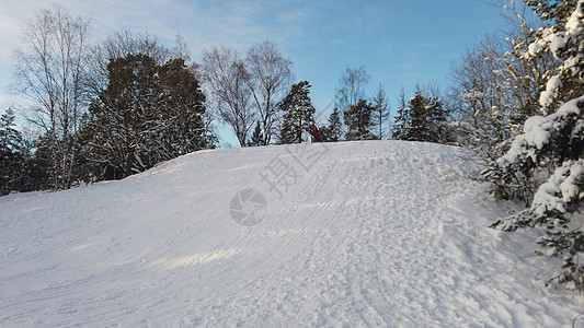 一个穿红色夹克的小男孩 在一个阳光明媚的清晨 在雪山下的床垫上图片