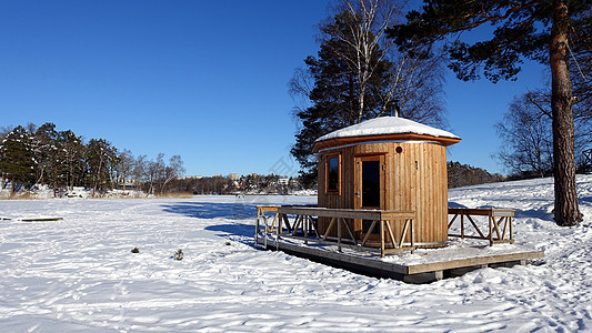 桑拿室在冰冻湖边准备蒸汽旅游风景房子建筑学松树天空蓝色建筑太阳图片