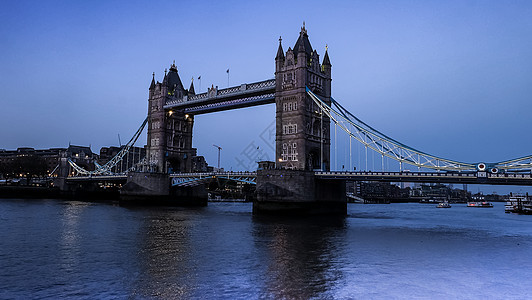 城市在夜幕中沿着著名的塔桥观光 蓝天空和泰晤士河的反射景观地标运输旅行工程旅游首都建筑天空历史图片