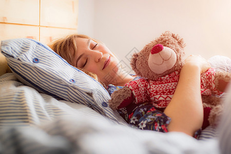 睡着休息 年轻女性睡在床上 泰迪熊玩具熊时间就寝纺织品午睡枕头说谎小孩女士毯子图片