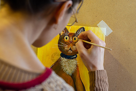 艺术家画了一幅猫的绘画 画在有丙烯酸涂料的壁架上 从艺术家背面看图片