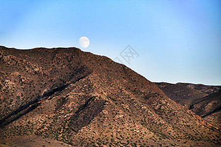 在火山山上偷窥月亮蓝色天空高度旅游岩石侵蚀地球顶峰风景晴天图片