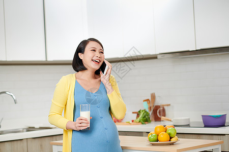 带着美味的橙子和用智能手机聊天的快乐怀孕妇女腹部成人婴儿母性厨房早餐母亲女士女性牛奶图片