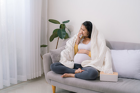 坐在墙对面的沙地上 身着感冒流感和感冒的有吸引力的孕妇鼻子流感母性腹部医疗女士怀孕母亲女性长椅图片
